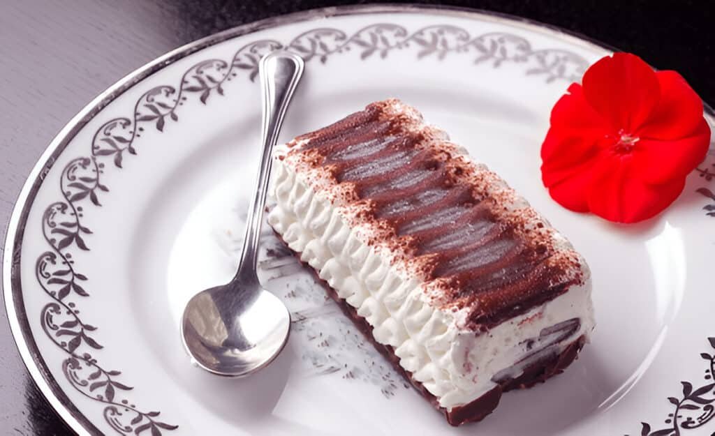 Decorated ice cream sandwich cake slice with spoon and red flower
