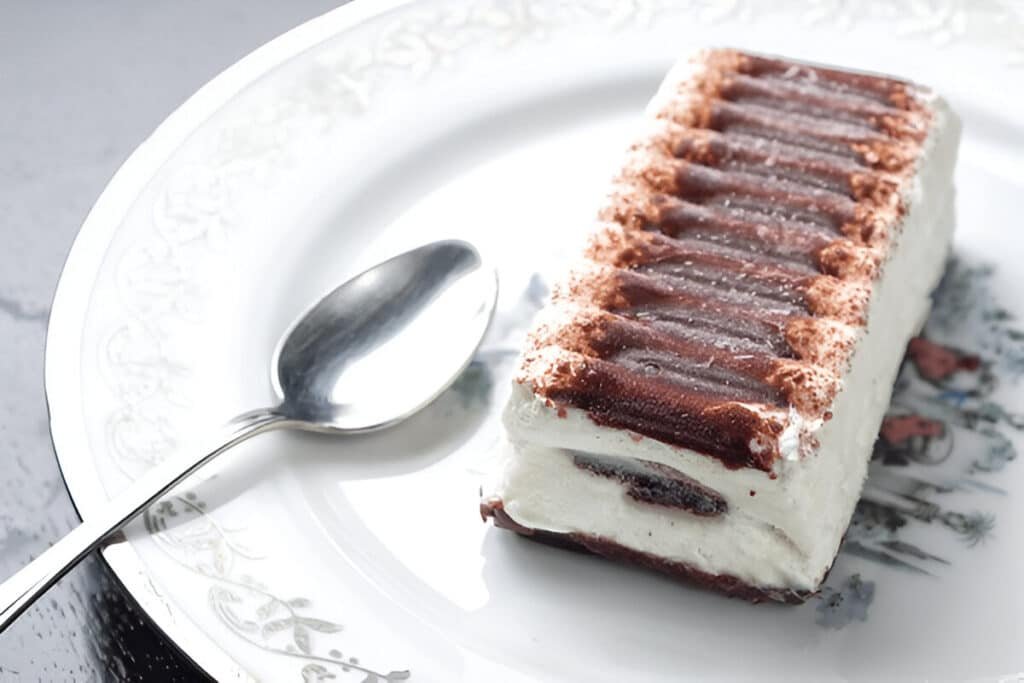 Frozen ice cream sandwich cake on a white plate with silver spoon