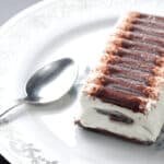 Frozen ice cream sandwich cake on a white plate with silver spoon