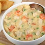 owl of creamy chicken pot pie soup with carrots, peas, and chunks of chicken.