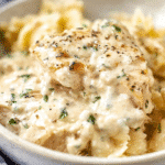 Creamy ranch chicken in a rich, creamy sauce served over bow-tie pasta in a rustic bowl.