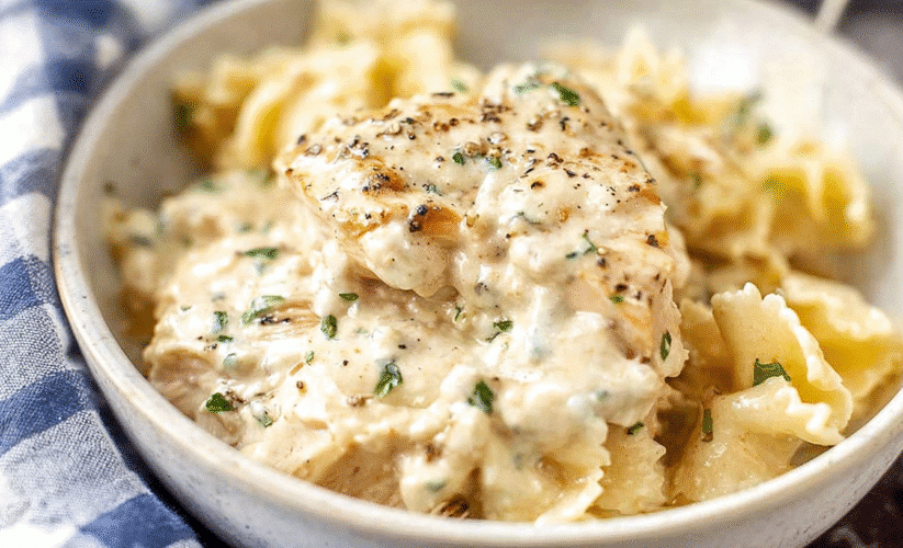 Creamy ranch chicken in a rich, creamy sauce served over bow-tie pasta in a rustic bowl.