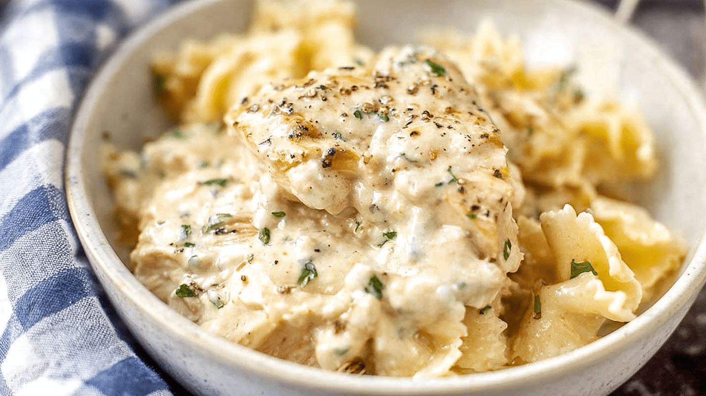 Creamy ranch chicken in a rich, creamy sauce served over bow-tie pasta in a rustic bowl.