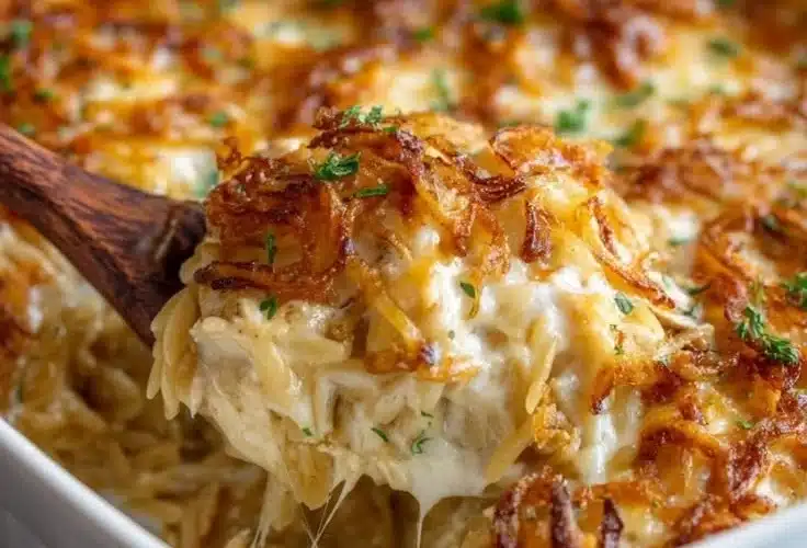 French Onion Chicken Orzo Casserole topped with melted cheese and fresh herbs