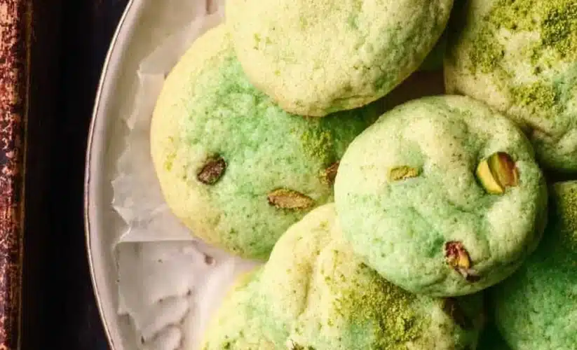 Baked pistachio pudding cookies on a cooling rack with green pistachios